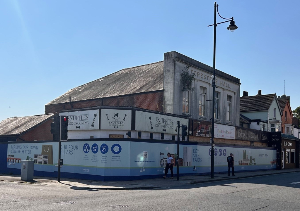 Photograph showing Foresters' Hall and the other buildings comprising 130 - 136 West Street, Fareham, wrapped in blue Fareham Borough Council hoarding holding details of the Regeneration of Fareham Town Centre.