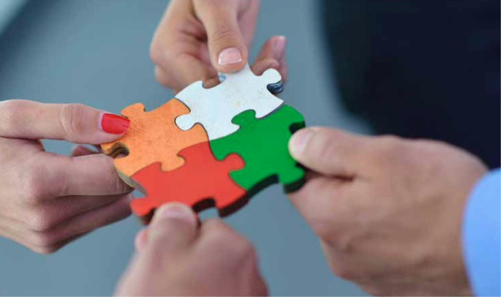 Four hands holding interlocking puzzle pieces